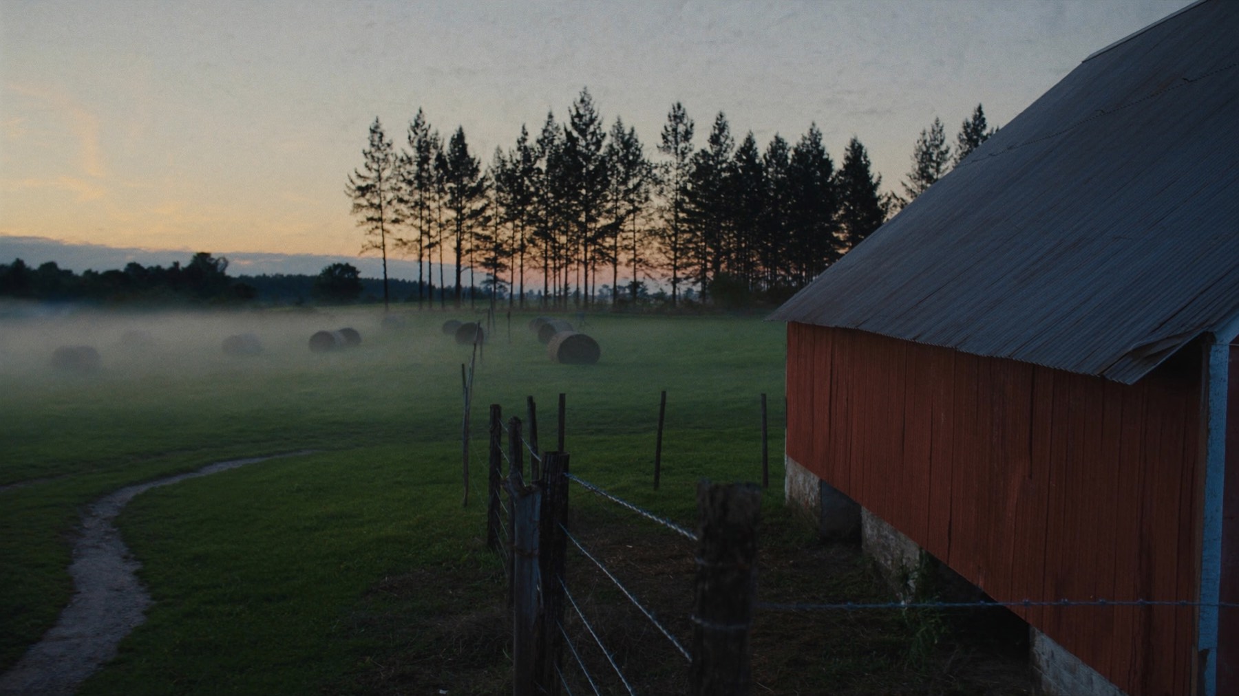 A small East Texas farm at dawn, red tin-roof barn and pasture under low ground fog